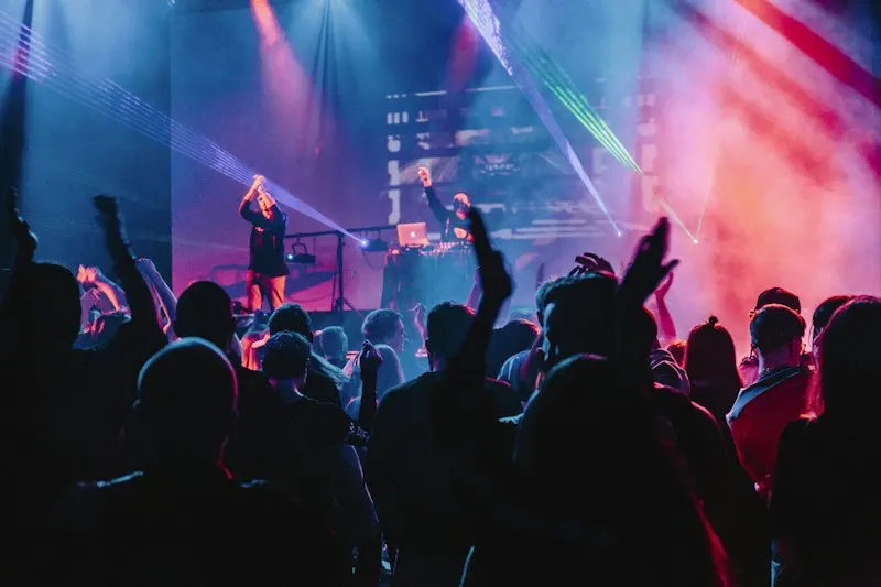 público con las manos en alto frente a un escenario iluminado
