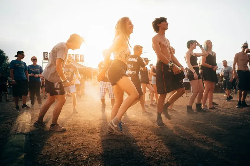 asistentes bailando al atardecer en un festival al aire libre