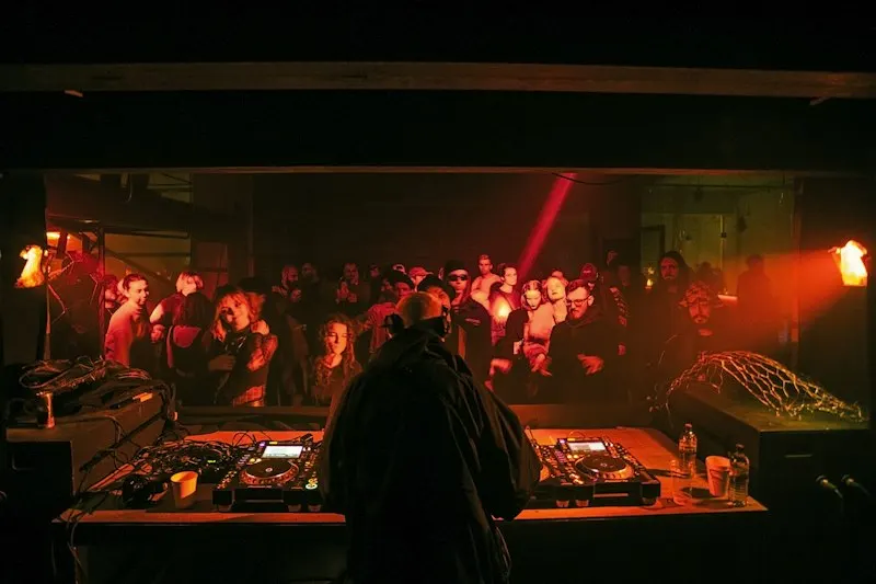 dj pinchando ante el público en un club con luz roja