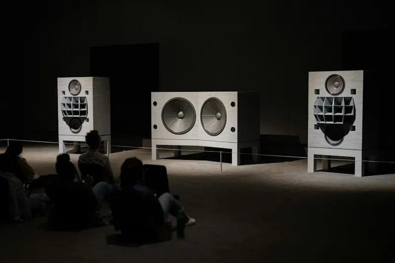 público sentado escuchando grandes altavoces en una sala oscura